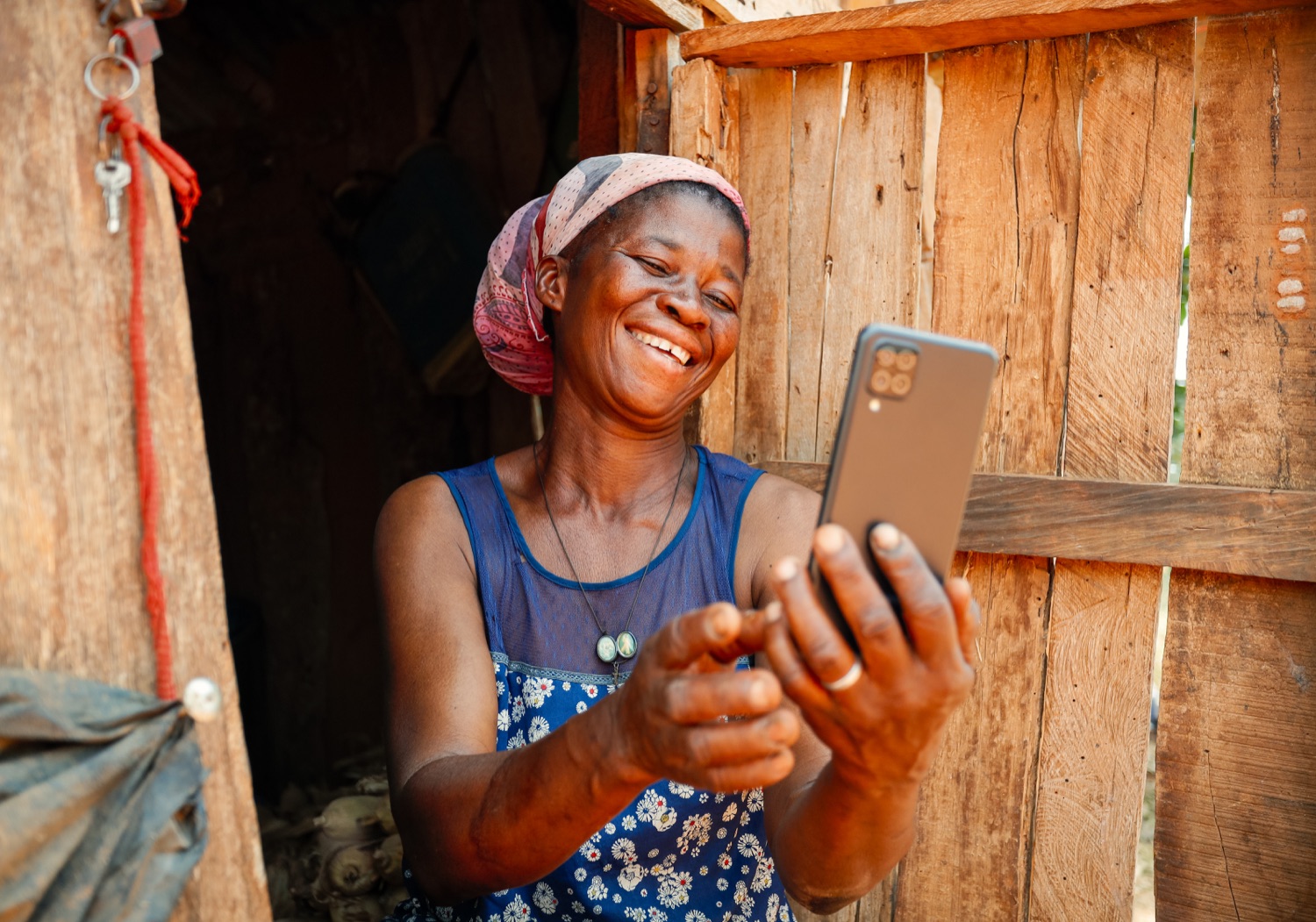 A woman smiling at a mobile phone in a doorway