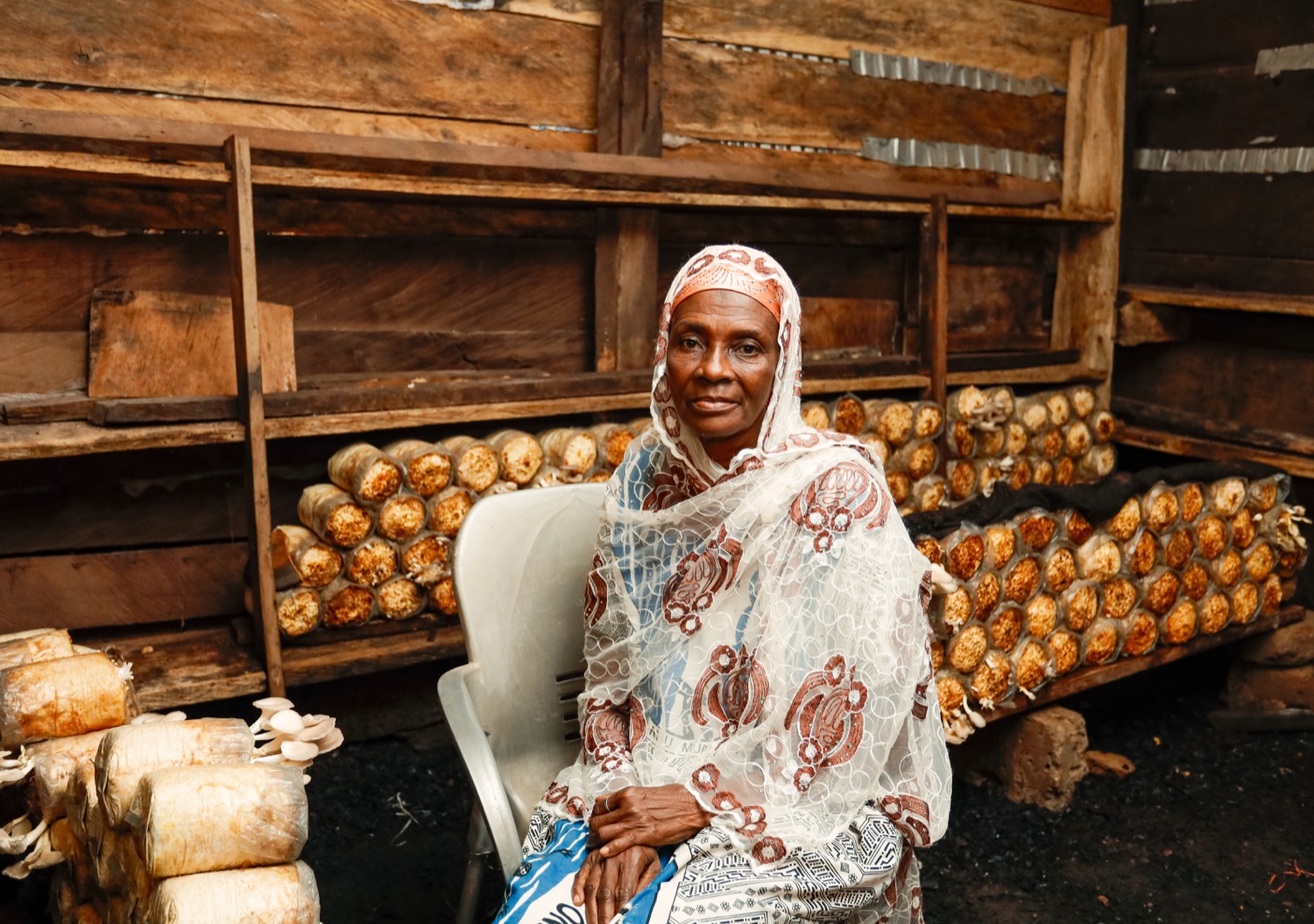 A woman seated at her mushroom farm