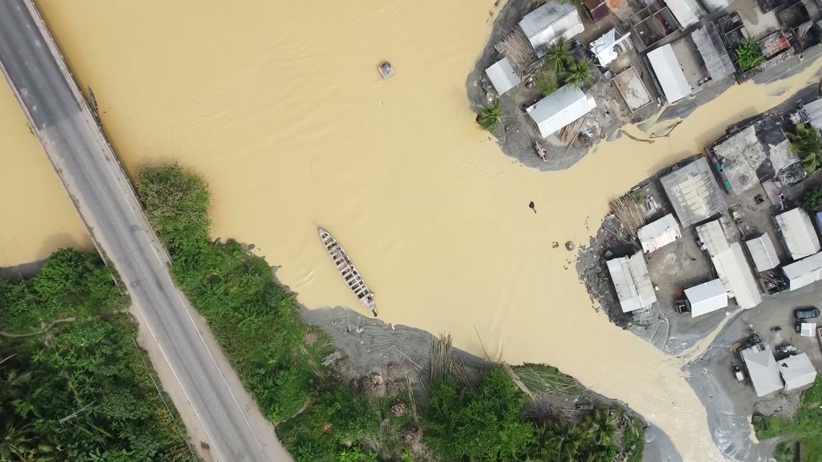 A river run yellow with mining runoff cutting through a town